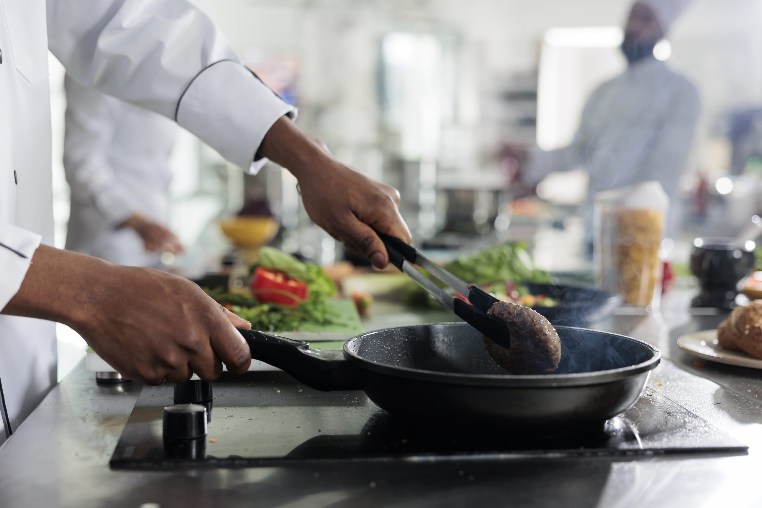 Gastronomy expert cooking succulent beef patty in hot pan while cooking gourmet dish for dinner service at restaurant.